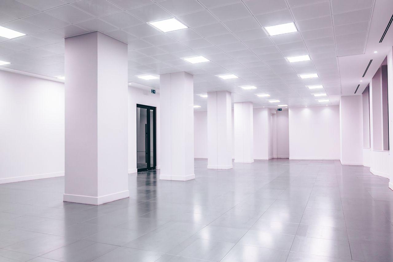 Wide-angle view of a modern minimalist white office space with clean lines and ample lighting.