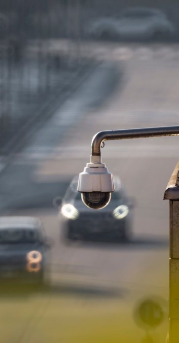 CCTV camera overlooking a busy street with cars in motion, capturing urban surveillance.