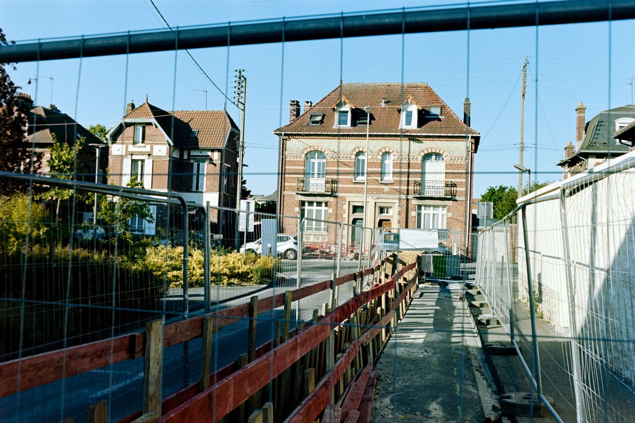 View of traditional French buildings in Compiègne with construction fencing in the foreground.