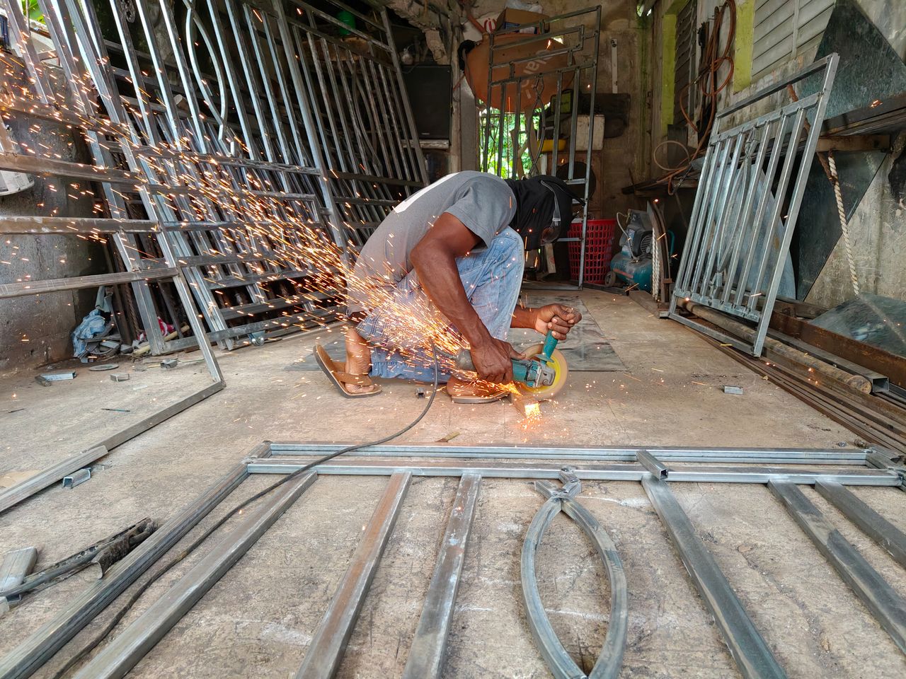 A professional using an angle grinder to cut metal, producing bright sparks in a workshop setting.