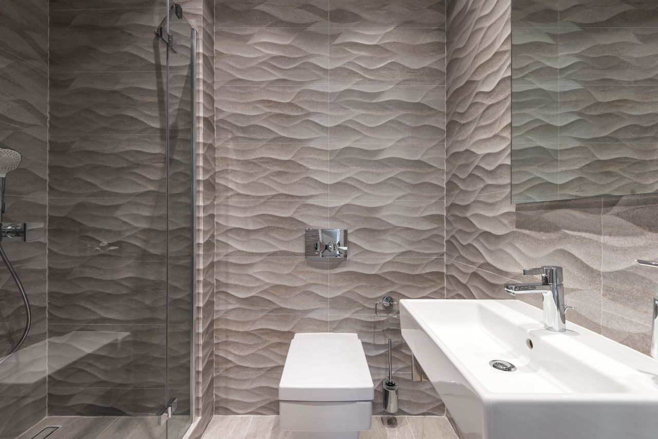 Sleek bathroom featuring textured walls, a glass shower, and a modern sink.