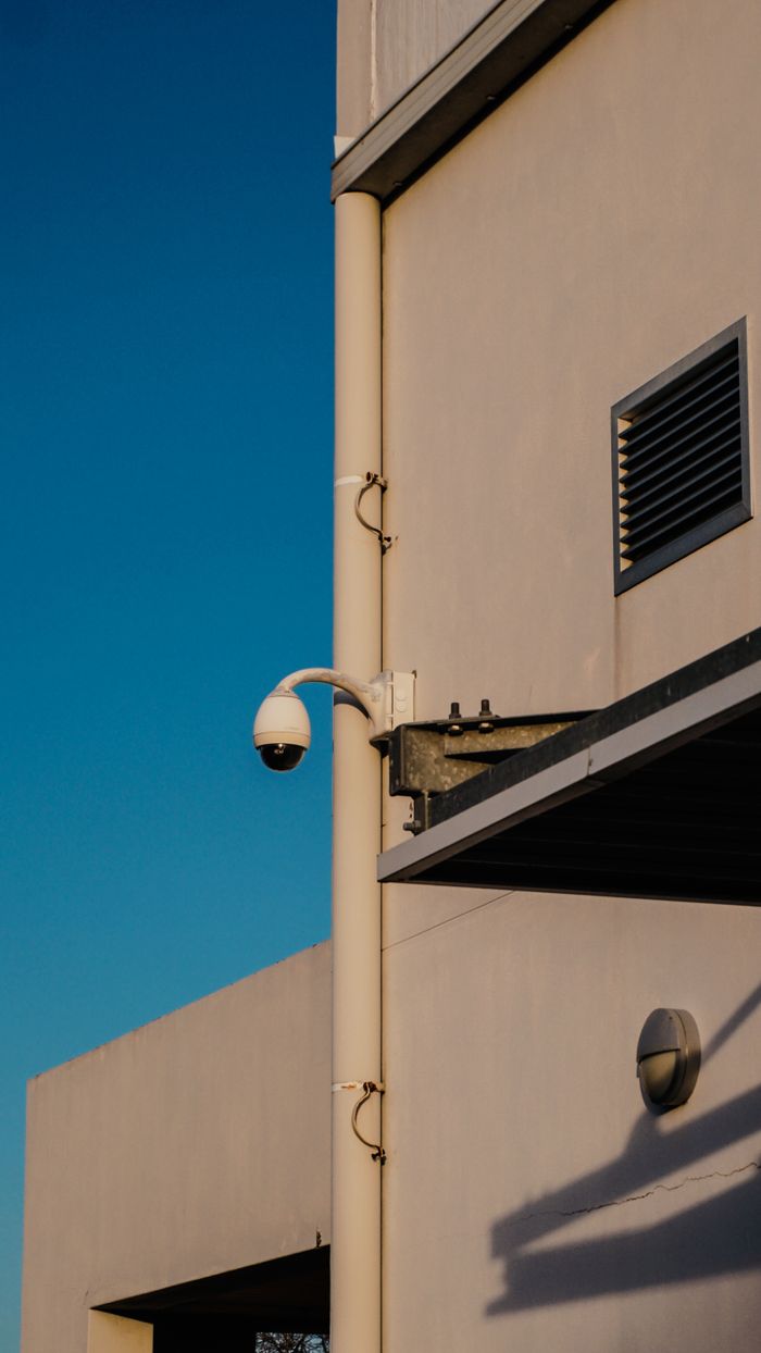 Security camera mounted on a modern building with clear blue sky backdrop in Cape Town.